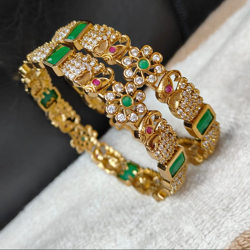 Gold bracelets with gemstones on a textured surface